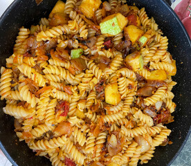 A large pot holds a vibrant mix of spiral pasta and various vegetables, ready to serve