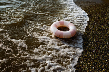 Pink and white life ring on a seashore