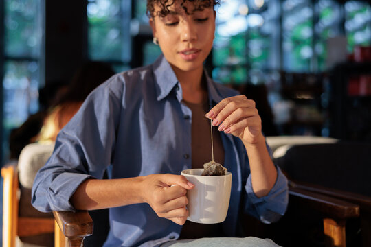 Woman steeping tea in a white mug.