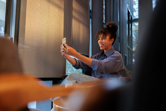 Woman takes a selfie in a modern, sunlit space.