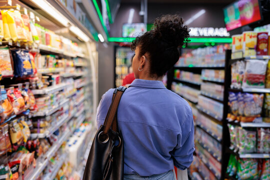 Woman shops in a grocery store aisle.