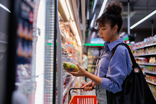 Woman shops for salad in a grocery store.
