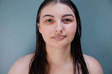 Portrait of a young woman with wet hair against a neutral background