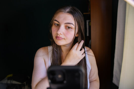 Young woman taking a selfie indoors with natural lighting from window