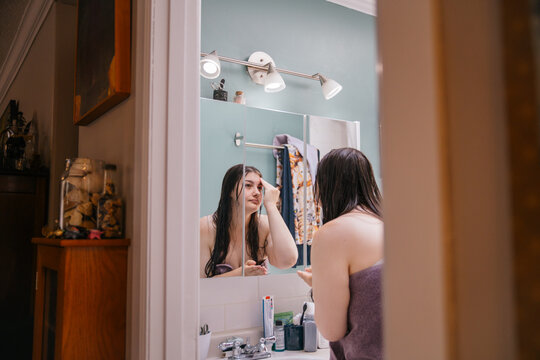 Young woman in a bathroom examining her reflection in the mirror