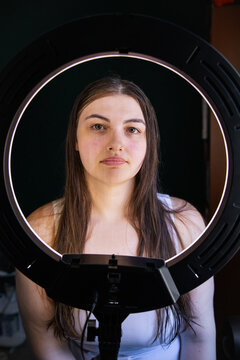 Portrait of a young woman framed by a circular ring light
