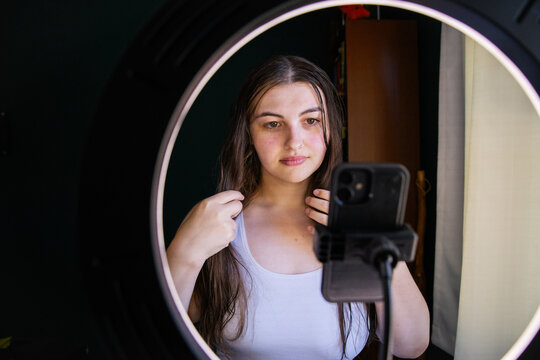 Woman preparing for a video with phone and ring light at home