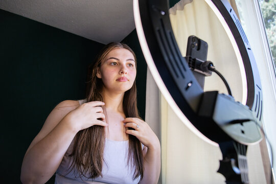Young woman setting up selfie ring light for social media 