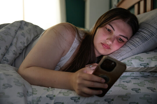 Young woman using a smartphone while lying in bed
