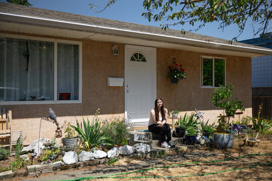 Young woman sitting on a porch surrounded by plants