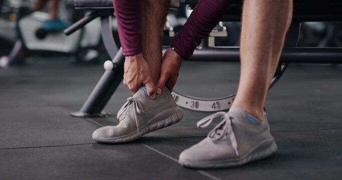 Person, hands and fitness with ankle injury for muscle tension, sprain or overworked in gym. Closeup, active or pain with sore foot or bone for strain, joint inflammation or accident in health club