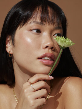 Woman Holding Flower Close to Her Face in Soft Lighting