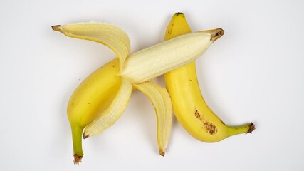 Top view of whole and half-peeled fresh yellow bananas rotating. Healthy organic tropical fruit with skin and flesh visible isolated on white background. - Powered by Adobe