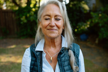 Calm senior woman outdoors in vest and necklace