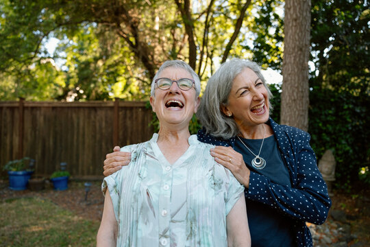 Friends laugh together in a sunny backyard garden moment