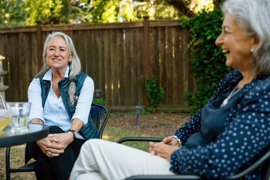 Friends chat in backyard garden, enjoying a sunny afternoon