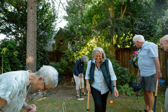 Happy seniors playing game in backyard garden with friends - Powered by Adobe