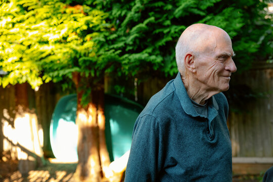Older man smiling in garden, casual shirt, peaceful day