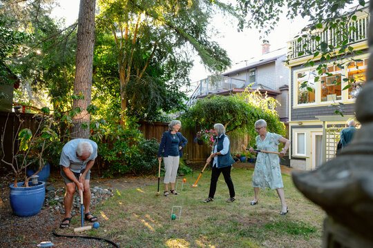 Neighbors play lawn croquet in sunny backyard gathering