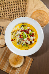 Chinese-style boiled fish fillets in a spicy yellow broth with chili, herbs, and vegetables, served in a white bowl with rustic table elements.
