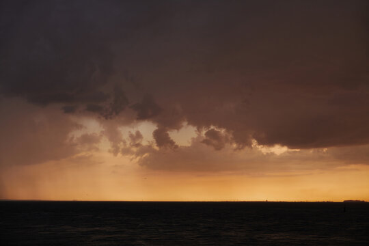 Storm clouds gather over the horizon at sunset