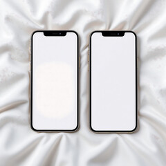 Elegant flat lay of two modern mobile devices with blank white screens for mockups, resting on a luxurious white satin background
