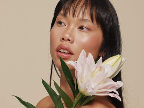 Portrait of a Woman Holding a White Flower on a Simple Background
