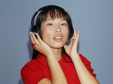 Woman Wearing Headphones Enjoys Music Against a Blue Background