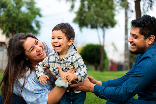 Parents Hugging and Laughing with Their Son Outdoors