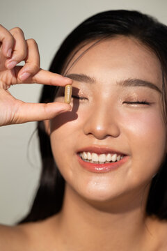 Woman holding a capsule with her eyes closed and smiling