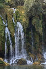 Kravice Waterfall in Herzegovina photographed on August 24, 2025, showing cascading streams over moss-covered rocks and lush vegetation.