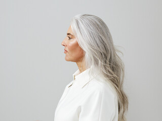 Profile View of a Woman With Long Gray Hair in a Neutral Setting