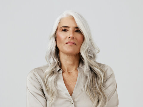 Portrait of a Confident Woman With Long Gray Hair in a Light Blouse