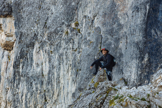 Climber Rests on Rocky Cliff in Mountain Landscape During Daylight