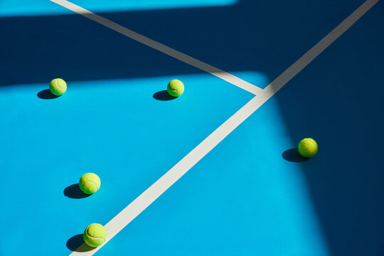 Tennis balls scattered on a bright blue court surface