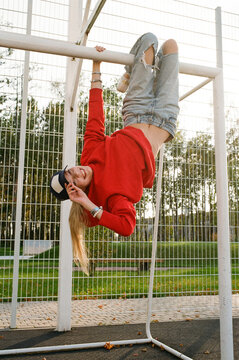 Playful woman hanging upside down on   football goals
