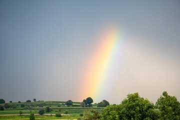 Rainbow arching over green rural landscape after storm