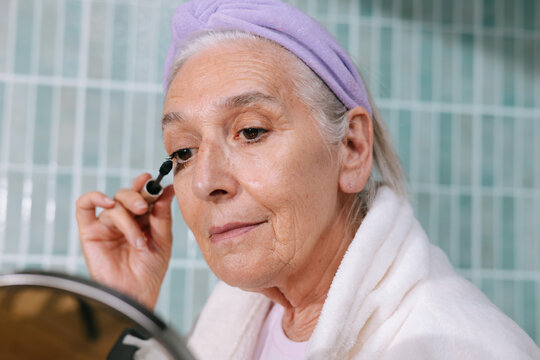 Senior woman applying mascara 