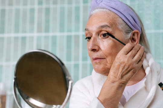 Senior woman applying mascara 