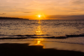 Golden Ocean Sunset with Dramatic Clouds. big Sun over the sea during a sunset with the sky coloured orange.