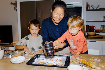Mother and children baking christmas cookies in kitchen