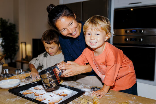 Family baking christmas cookies, sprinkling sugar together