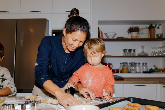 Mother and child baking christmas cookies in kitchen