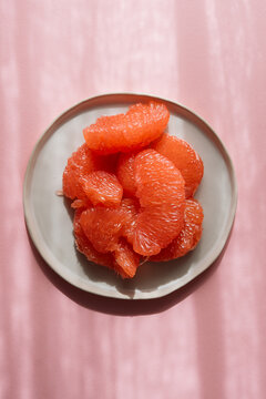 Plate of citrus with bright pink background