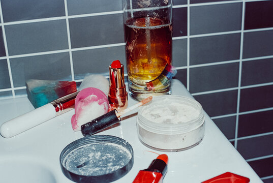 makeup tools and glass with a mixed drink on the sink, 35mm film