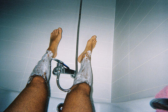 a man in a bathtub with hairy legs covered in shaving foam, 35mm film