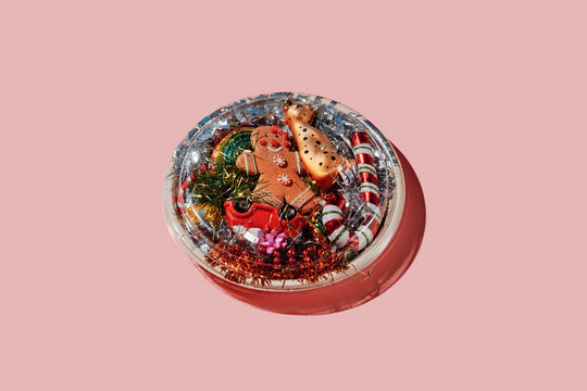 a round container with christmas ornaments on a pink surface