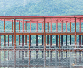 Under Construction Steel Building with Red Frames and Mountains