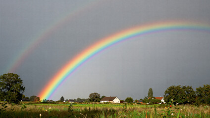 Obraz premium Captivating double rainbow over a serene countryside landscape nature photography vibrant colors peaceful environment