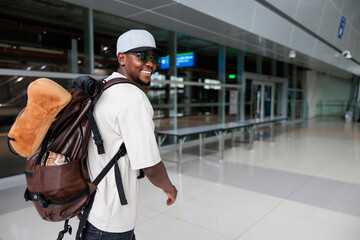 Smiling traveler with backpack in airport terminal.